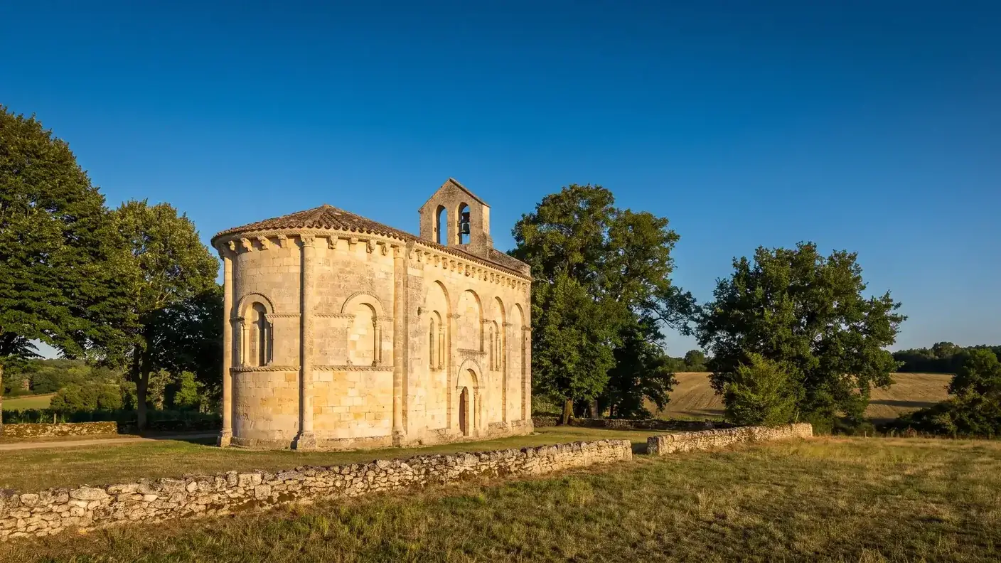 Une petite église romane du XIIe siècle en pierre calcaire couleur de miel en Gironde, chevet arrondi et clocher