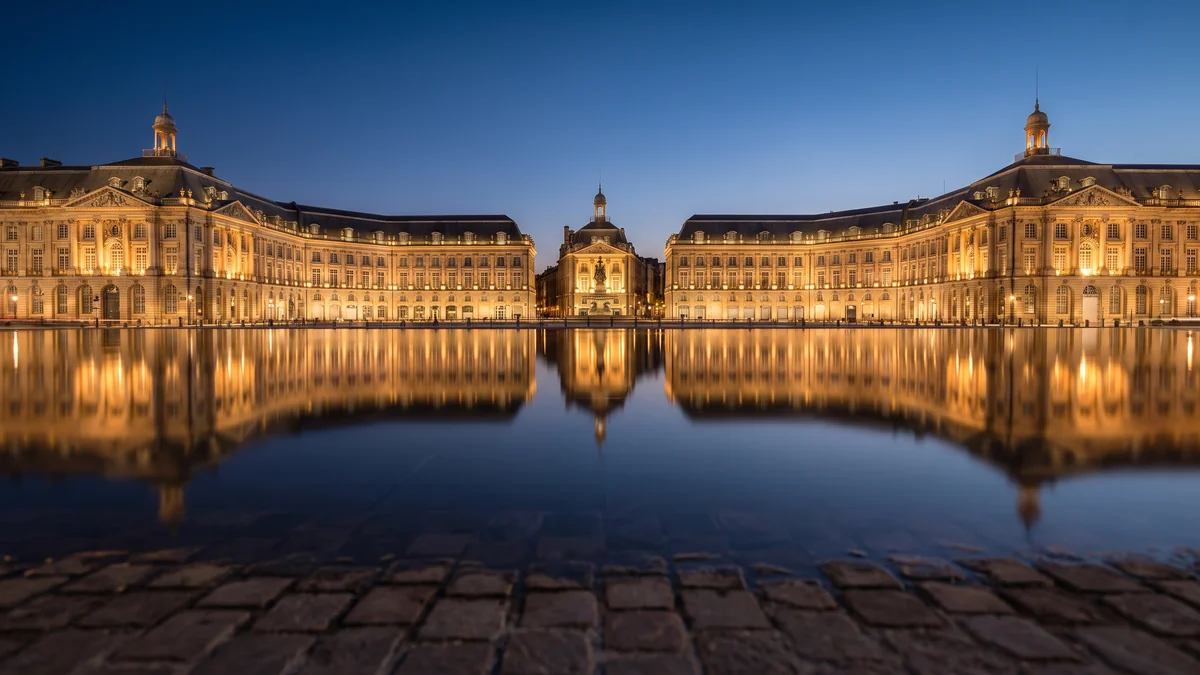 Place de la Bourse reflétée dans le Miroir d’eau de Bordeaux à la nuit tombée