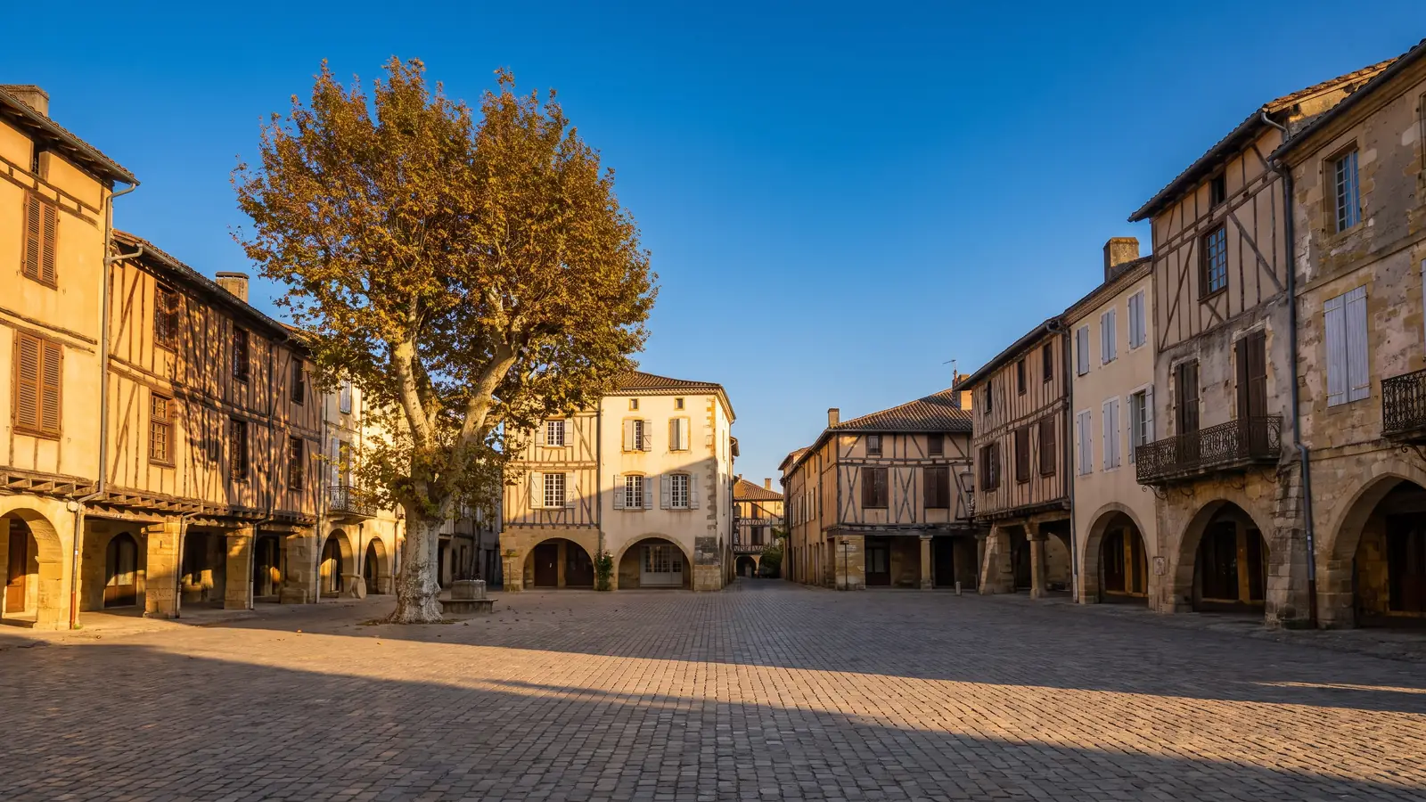 Maisons à colombages et arcades sur une place gasconne