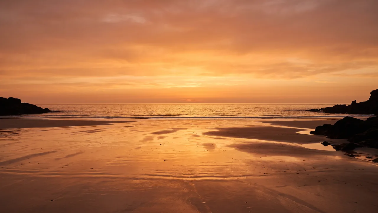 Coucher de soleil orangé sur l'horizon de l'Atlantique depuis une plage déserte d'Hourtin, sable humide réfléchissant