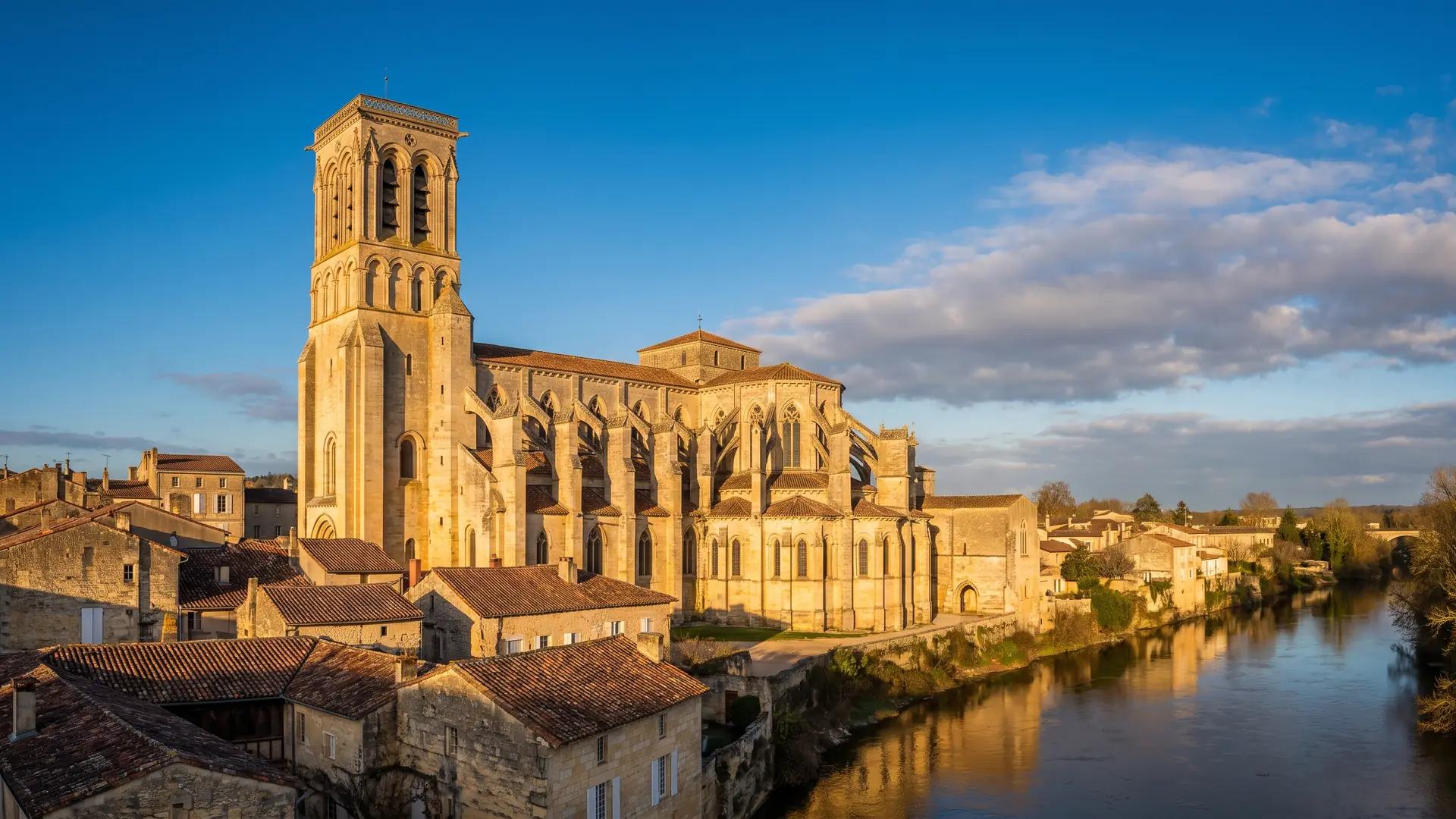 Une grande église de prieuré en pierre dorée dominant les toits d'une ville au bord de la Garonne, en Gironde