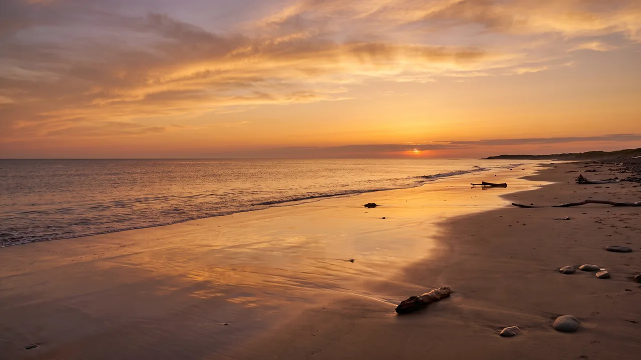 Coucher de soleil orangé sur l'horizon de l'Atlantique depuis la plage sauvage du Porge, eau calme et sable humide
