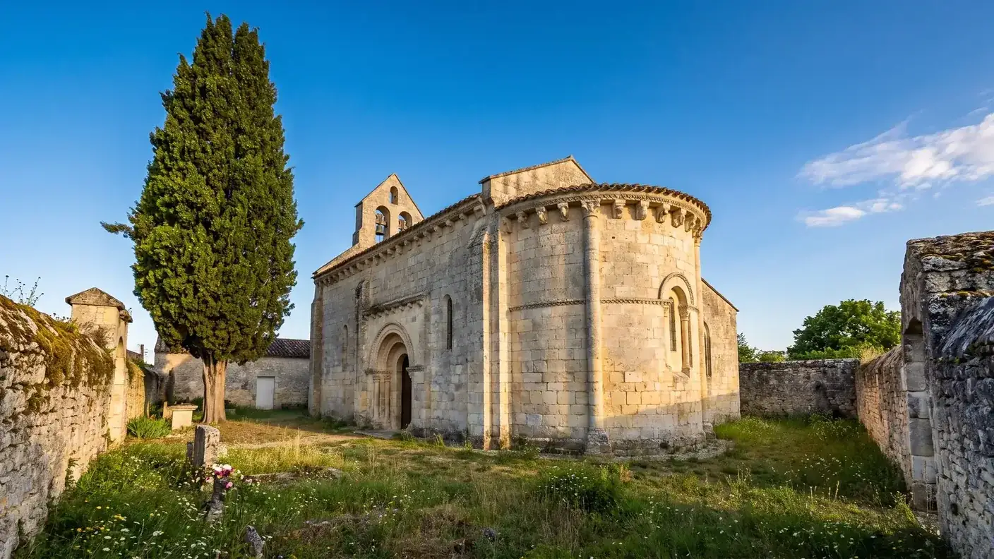 Une église romane saintongeaise en pierre calcaire claire, abside arrondie à modillons et arcatures en plein cintre