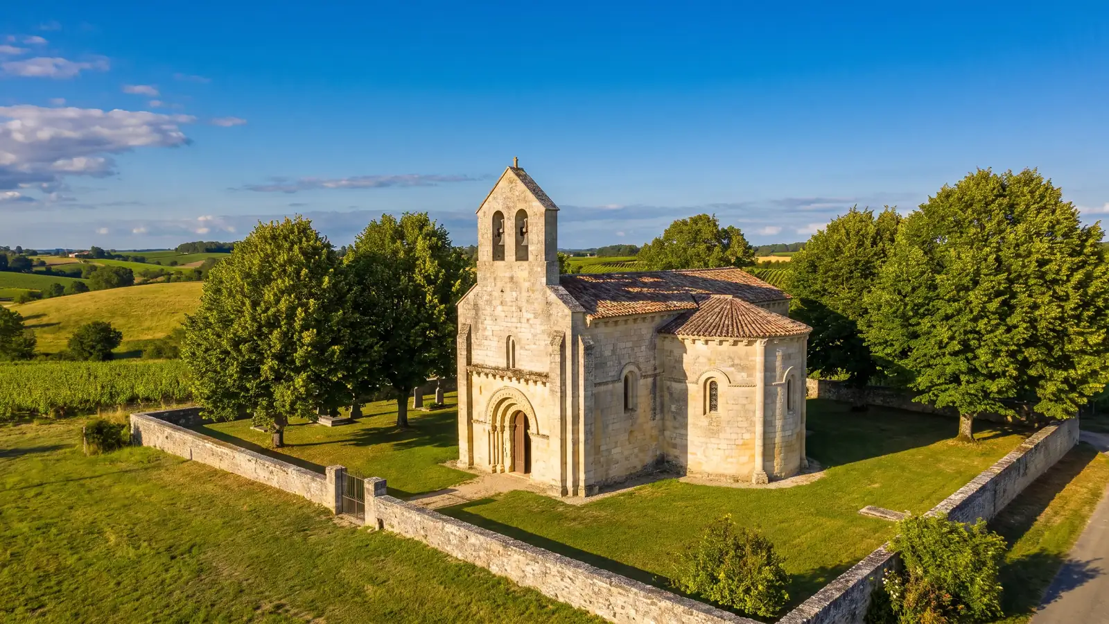 Une petite église romane du XIe-XIIe siècle en pierre couleur de miel, chevet arrondi et clocher de village