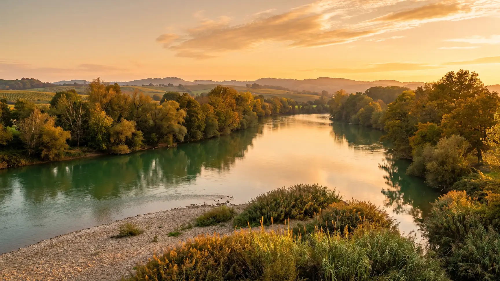 Une rivière verte et calme, un gave bordé d'arbres, serpentant dans le Pays d'Orthe, dans les Landes