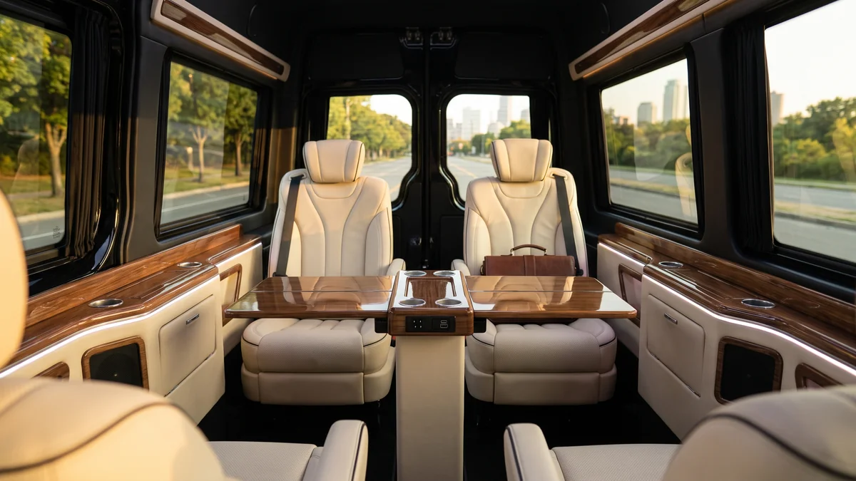 Intérieur d'un van avec sièges cuir, prises et espace pour travailler à bord