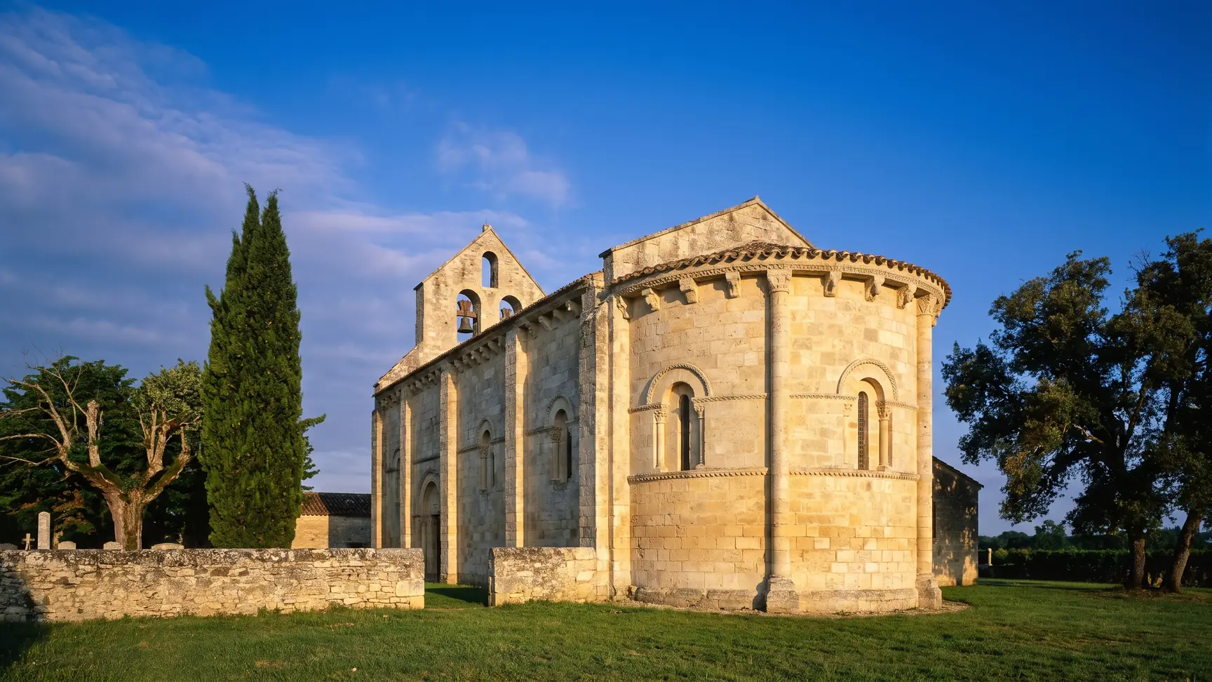 Une petite église romane du XIe-XIIe siècle en pierre couleur de miel, chevet arrondi à corbeaux sculptés et clocher
