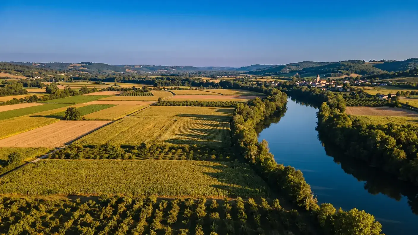 La large vallée de la Garonne autour de Tonneins, damier de champs et de vergers, le fleuve serpentant entre ses rives